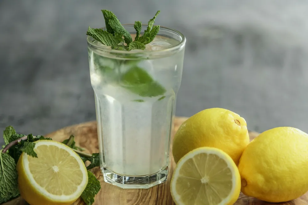 Verre de citronnade glacée posé près de citrons coupés